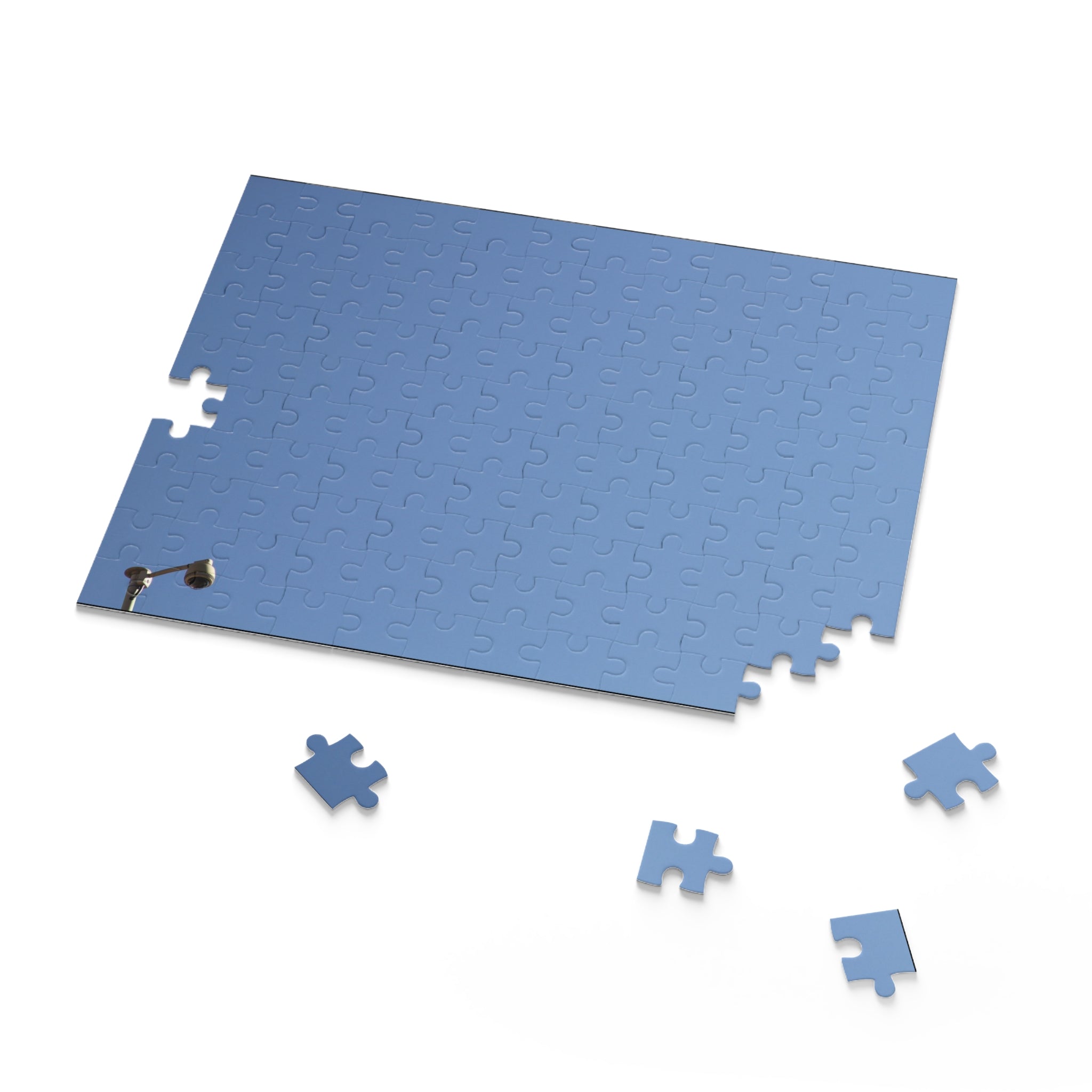 Blue puzzle mat with scattered pieces on a white background