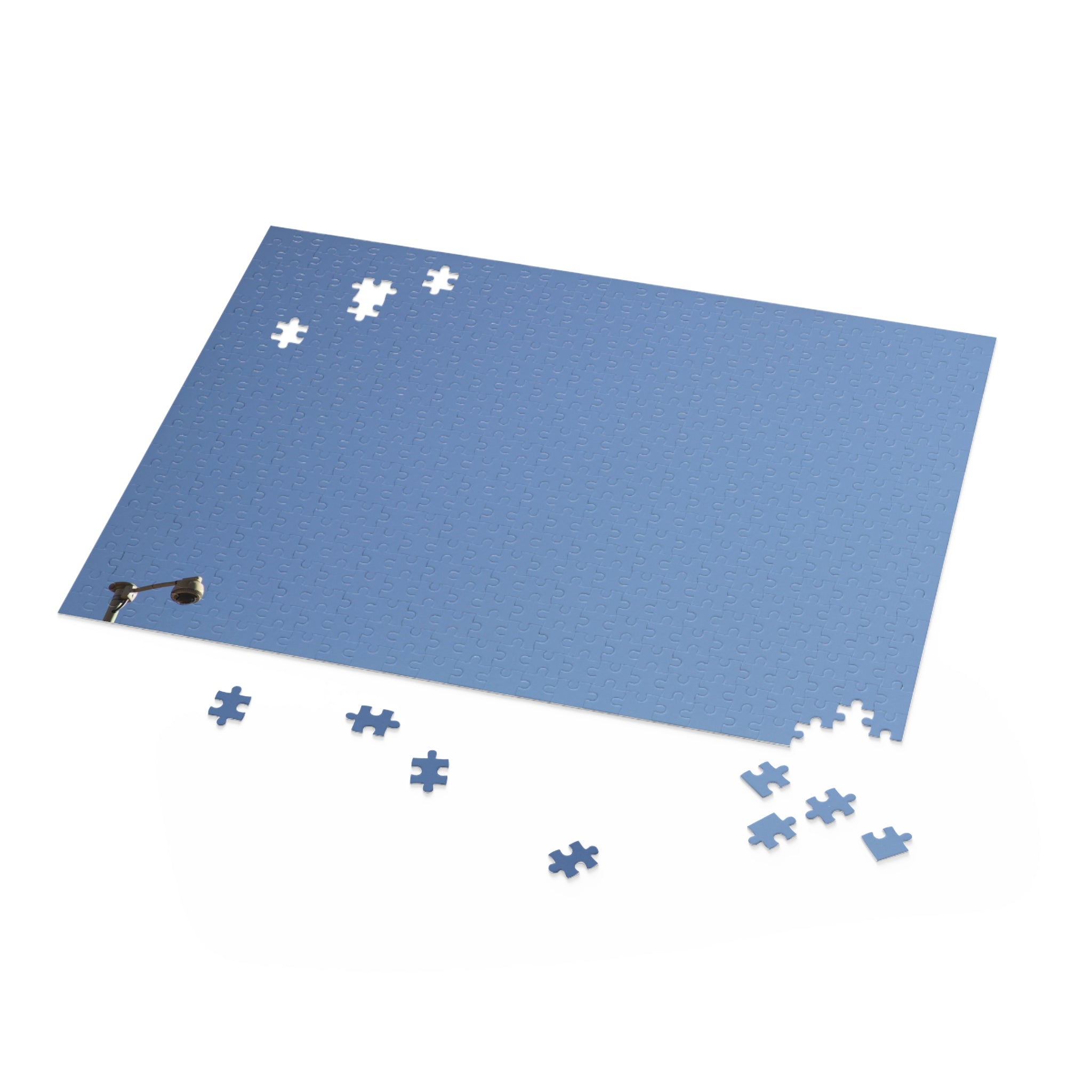 Blue puzzle mat with scattered puzzle pieces on a white background