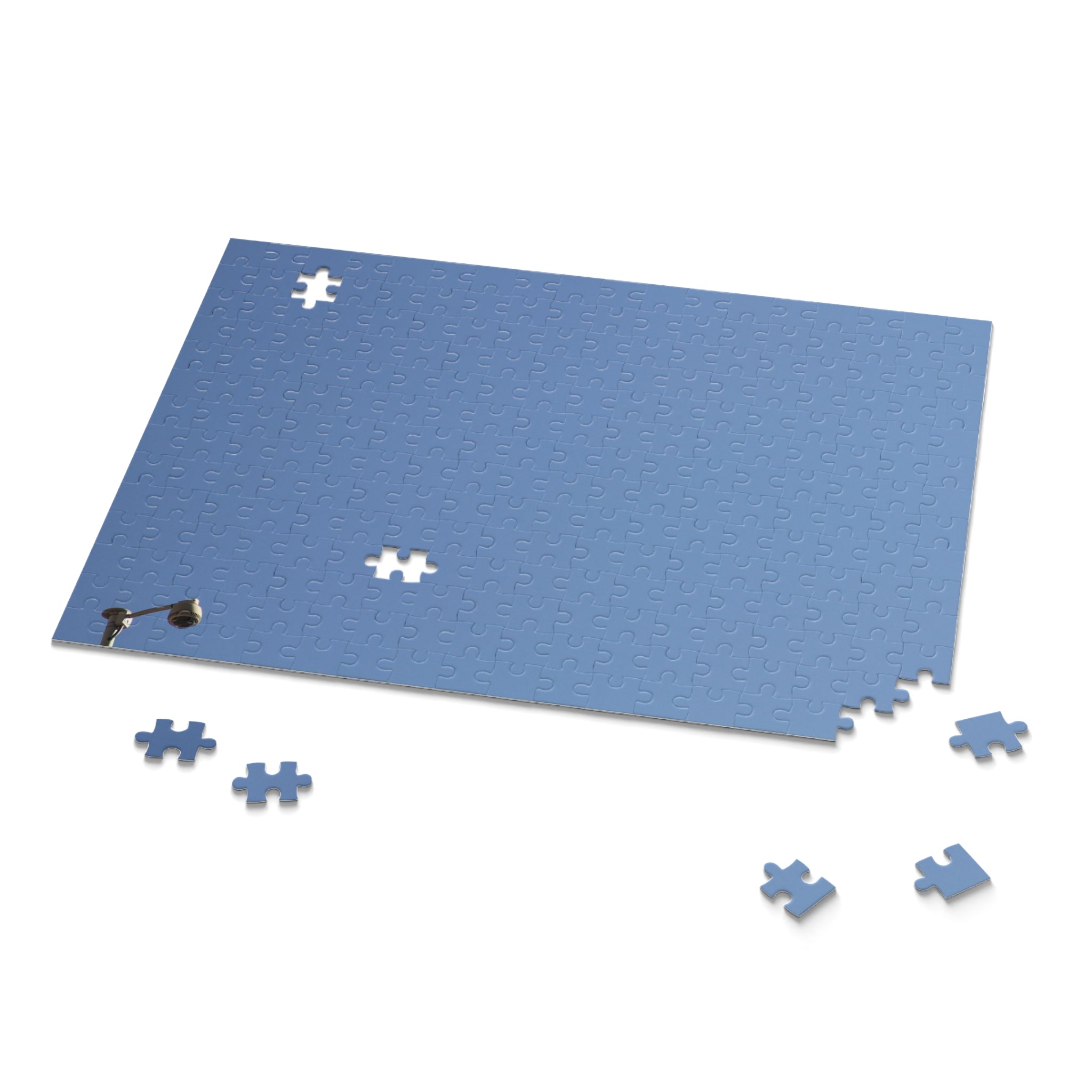 Blue puzzle mat with scattered puzzle pieces on a white background