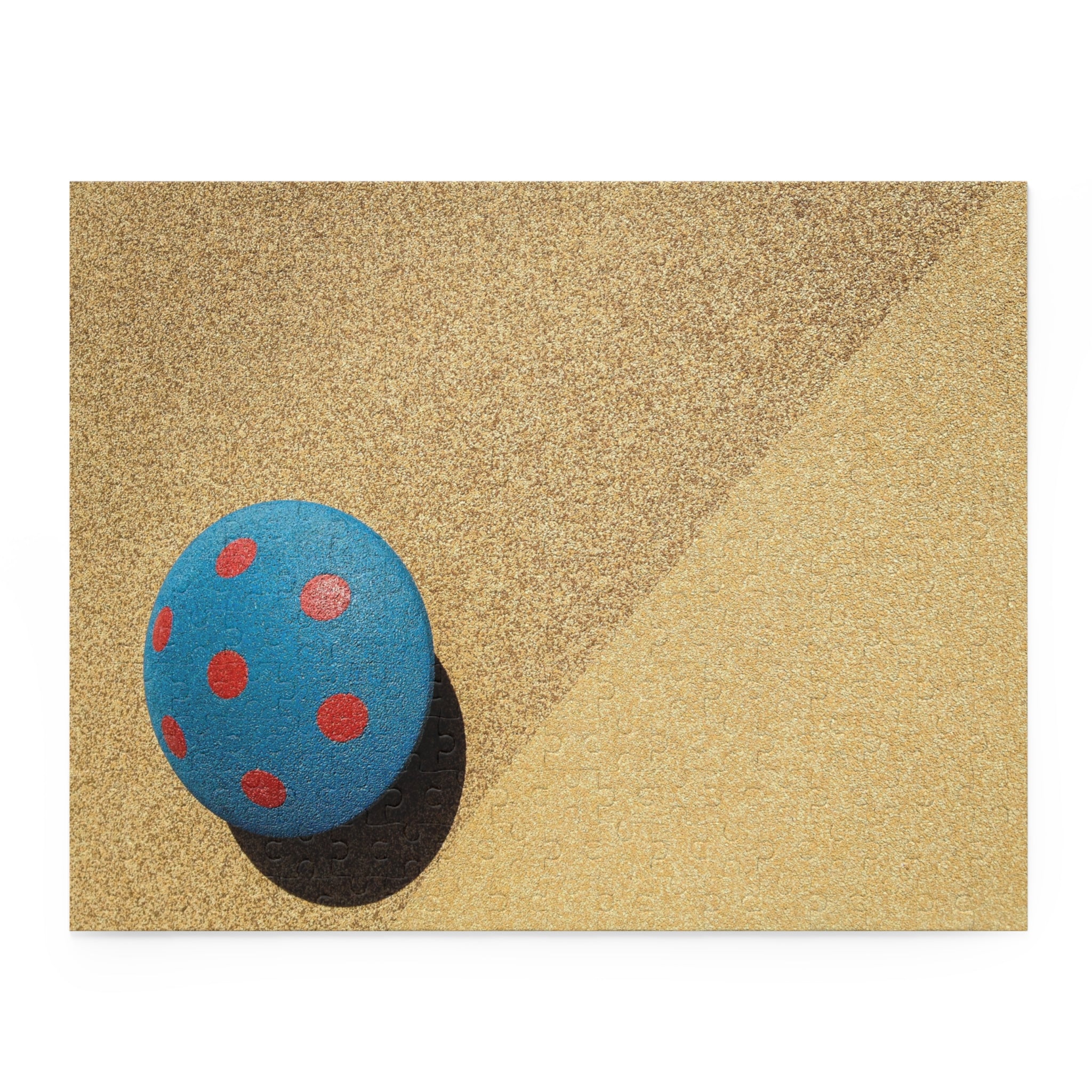 Blue ball with red spots on a textured beige surface
