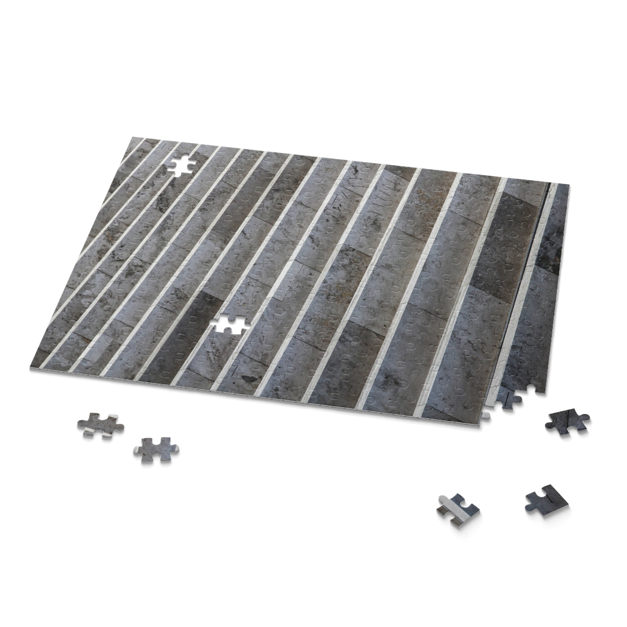 Gray and black striped puzzle mat with scattered puzzle pieces on a white background