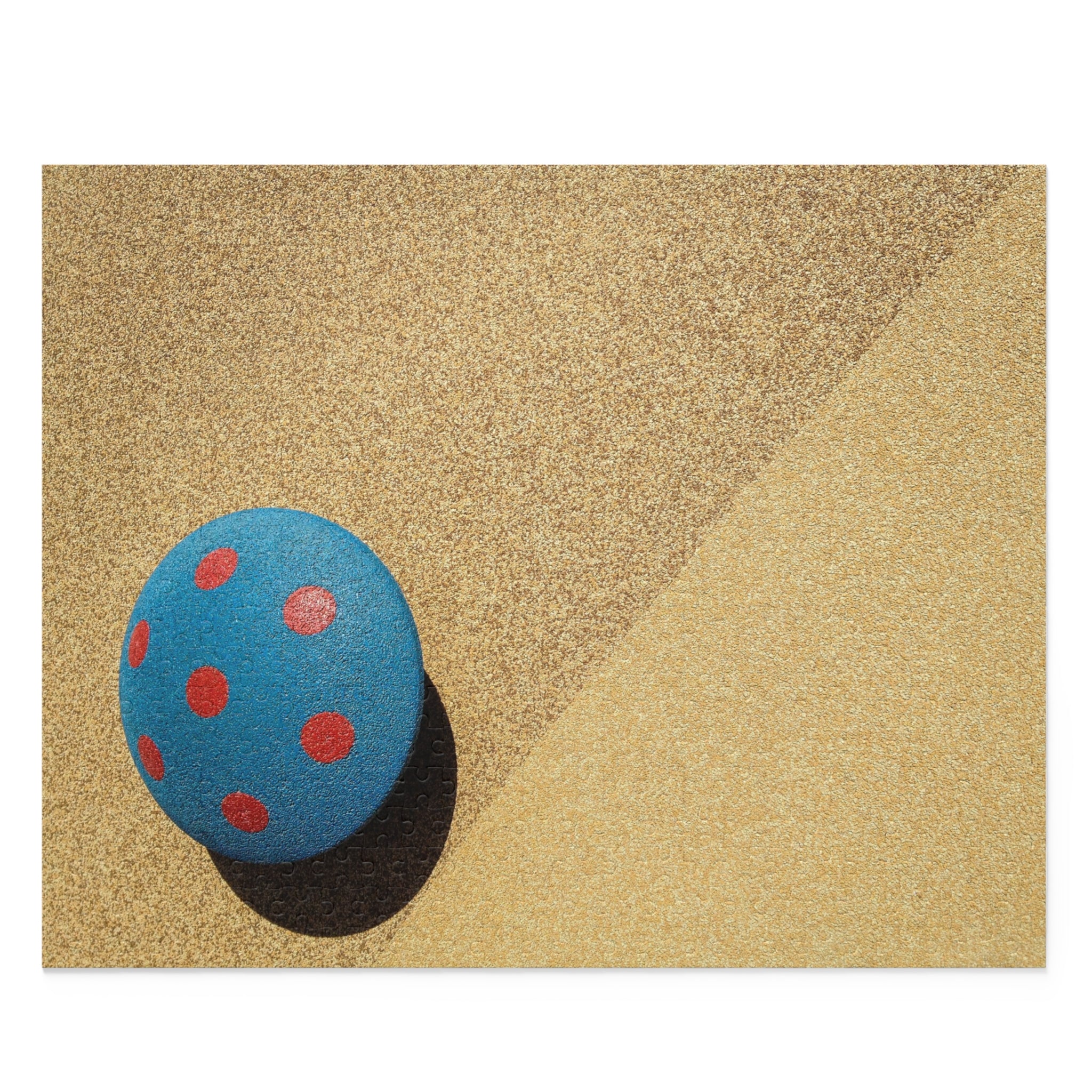 Blue ball with red spots on a textured beige surface